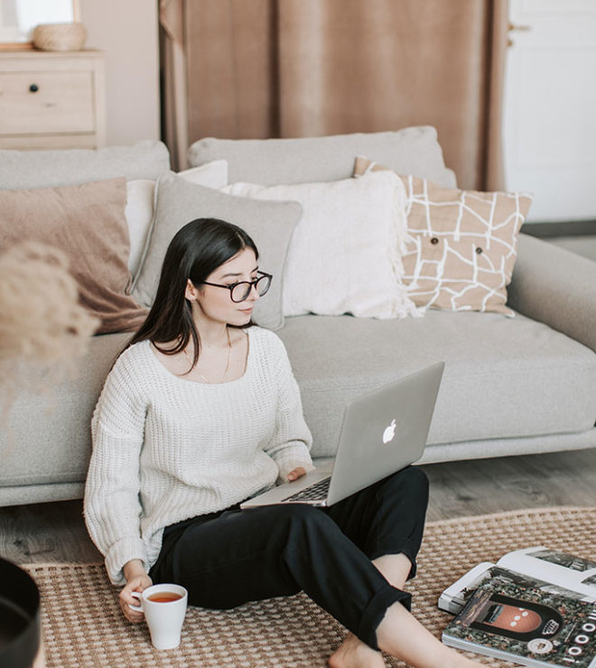 digital marketing in education sector girl in glasses sitting on the floor with coffee and laptop