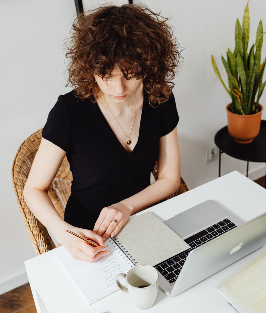 fintech marketing agency girl at the laptop writing down to the notepad