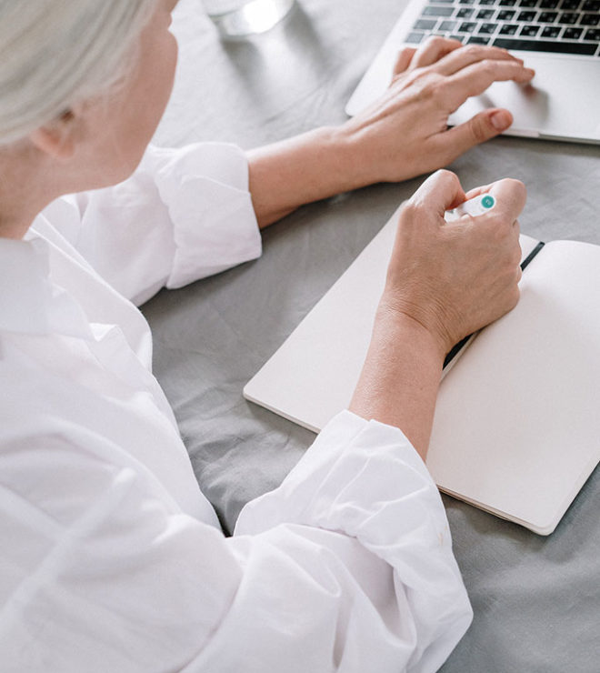 healthcare digital marketing service doctor with gray hair typing at the laptop