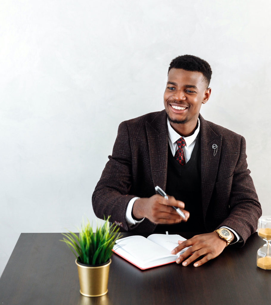 internet marketing agency for attorneys afro american man in suit writing something at the table with a room flower in the office