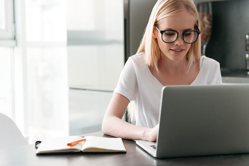 concentrated young lady working with laptop home