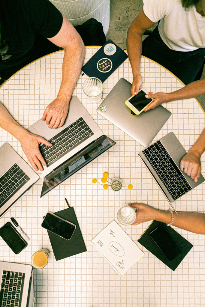 laptops and tablets on the office table and people sitting around