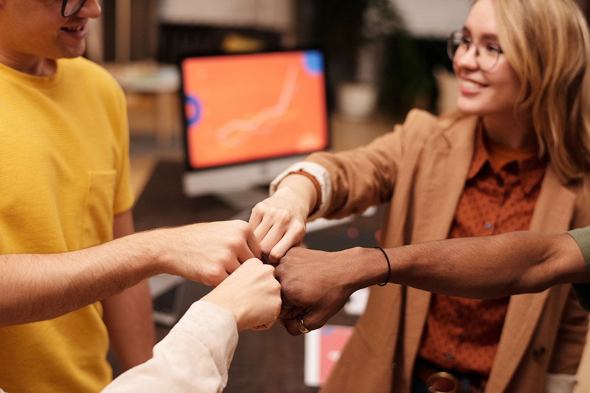 people of different nations holding fists together as a team